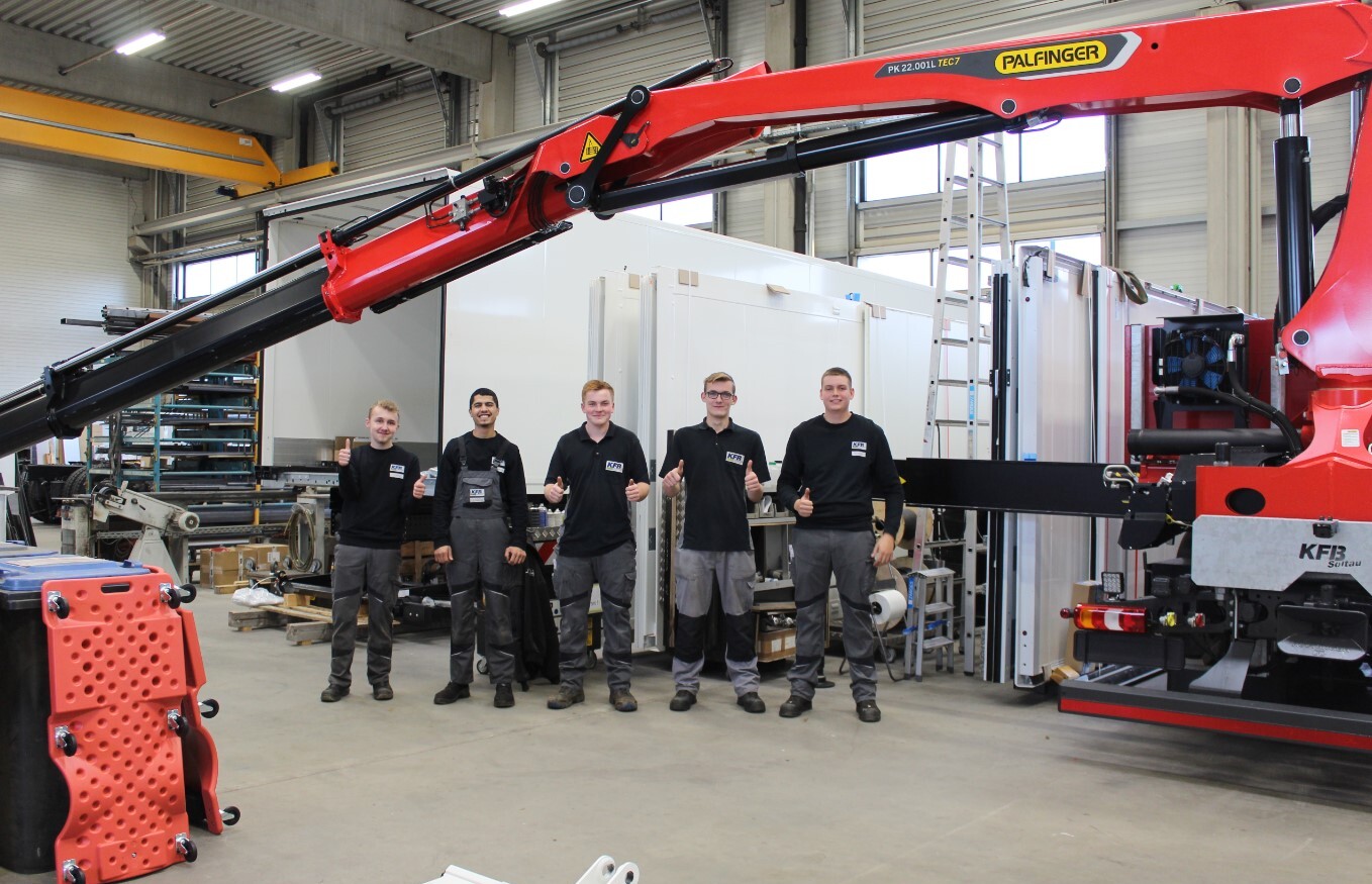 Die Beschäftigten von KFB Soltau stehen neben einem schweren Gerät.