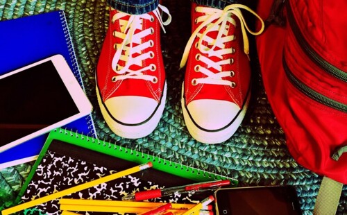 Turnschuhe, Rucksack und ein Handy liegen auf dem Teppich. Turnschuhe, Rucksack und ein Handy liegen auf dem Teppich.