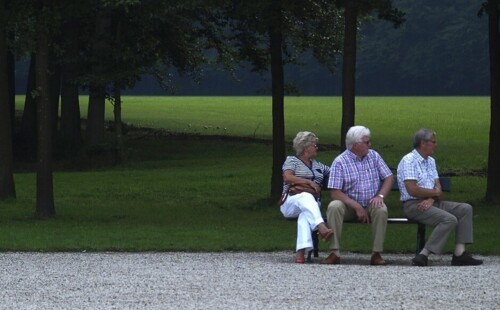 Drei ältere Menschen sitzen auf einer Bank und schauen in die Ferne. Drei ältere Menschen sitzen auf einer Bank und schauen in die Ferne.