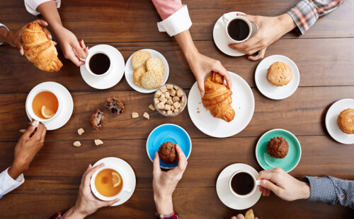 Auf einem Tisch stehen Tee- und Kaffeetassen sowie Kekse und Croissant. Auf einem Tisch stehen Tee- und Kaffeetassen sowie Kekse und Croissant.