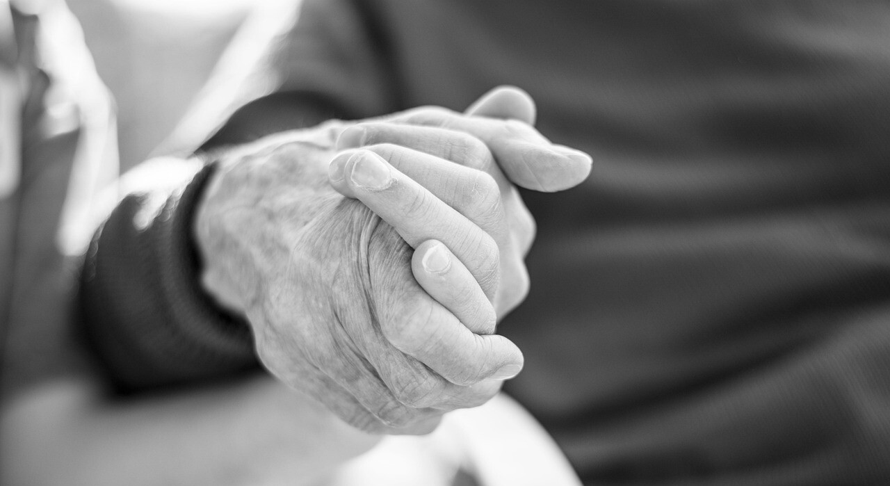 Eine junge und eine alte Hand halten einander fest. 