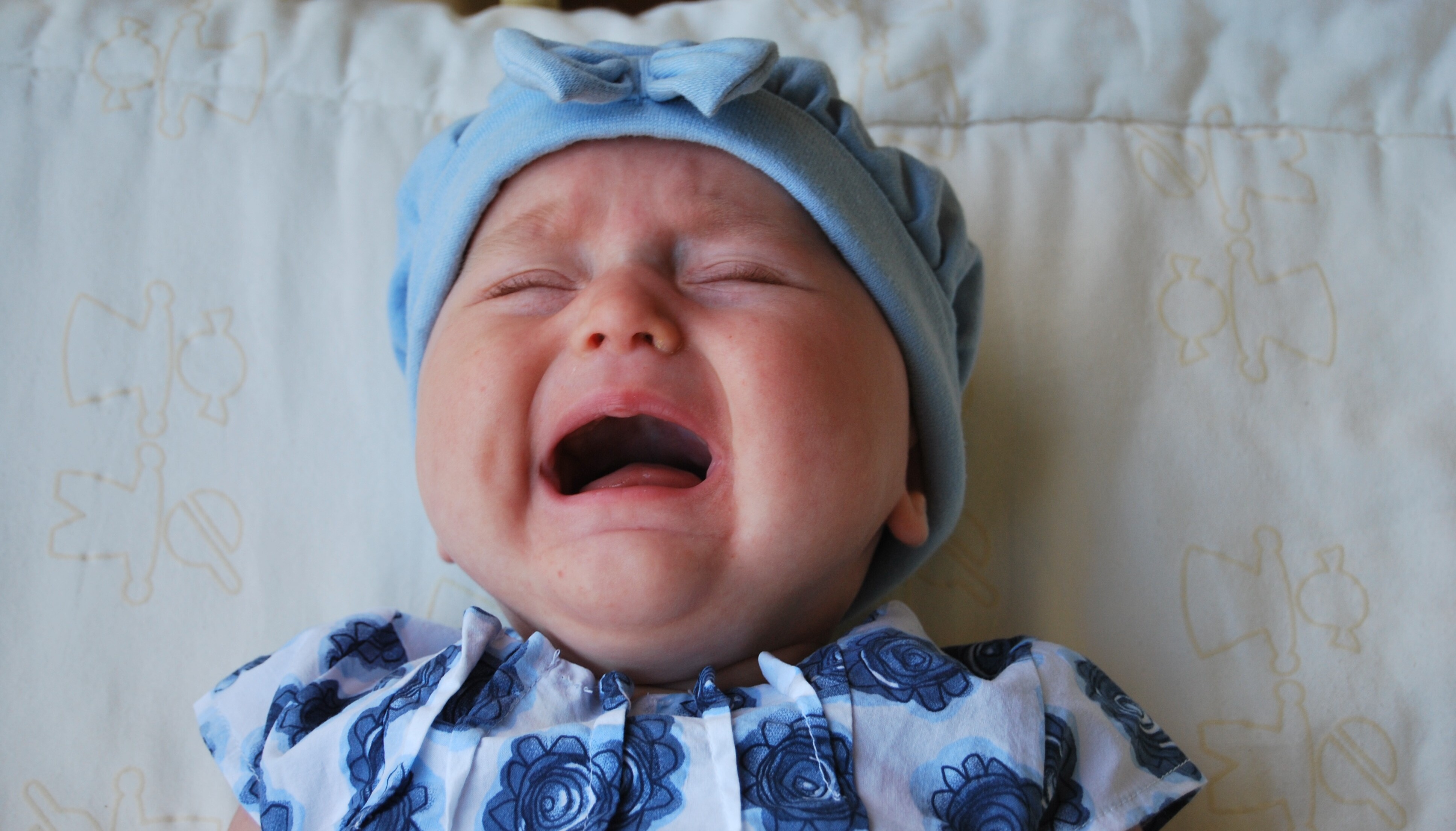 Ein Baby liegt auf einem Fell und schreit.