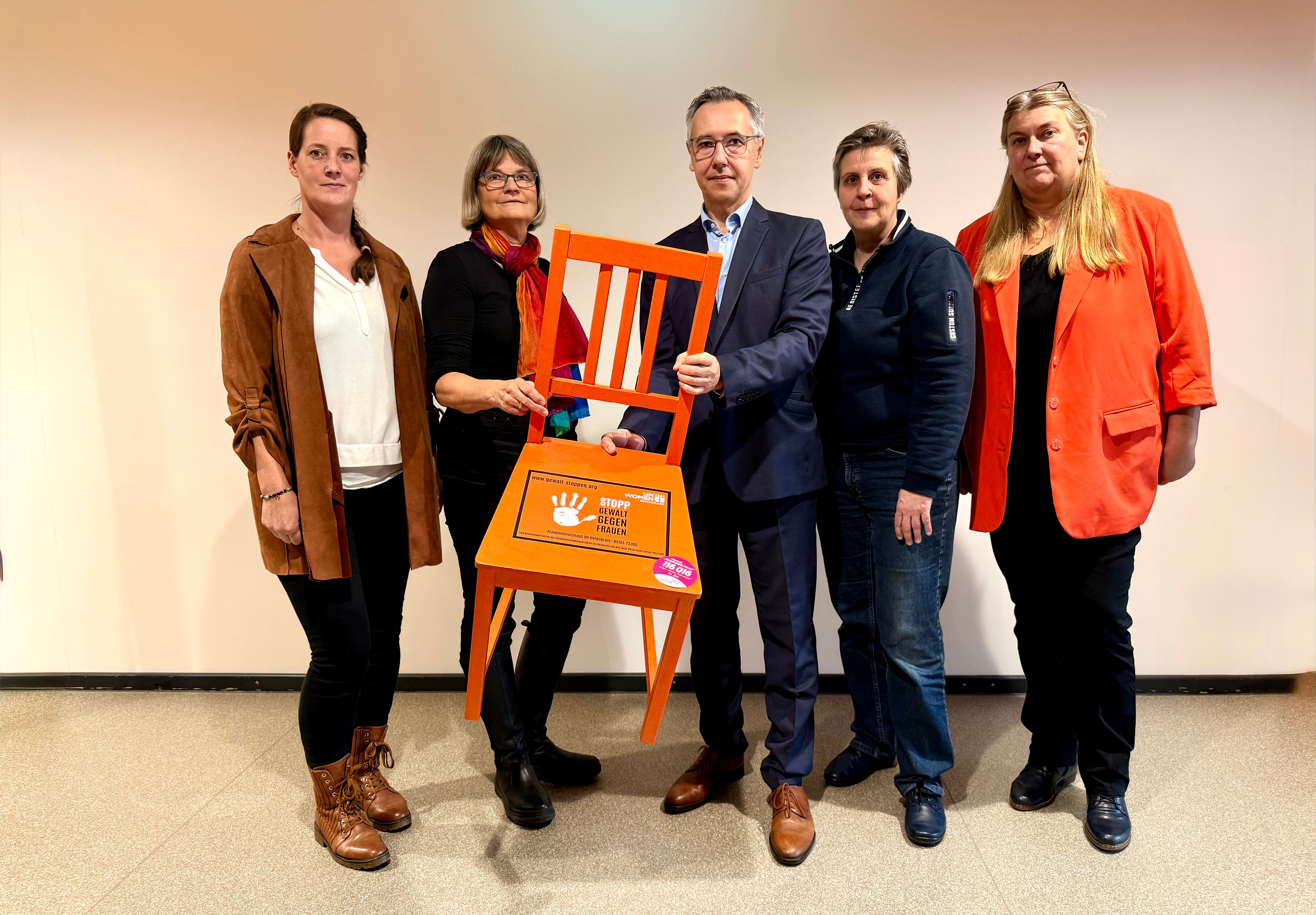 Gleichstellungsbeauftragte und der Landrat präsentieren einen Stuhl in der Farbe Orange. Gleichstellungsbeauftragte und der Landrat präsentieren einen Stuhl in der Farbe Orange.