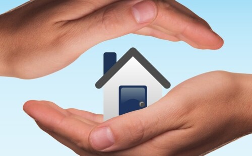 Zwei Hände halten ein Haus. 