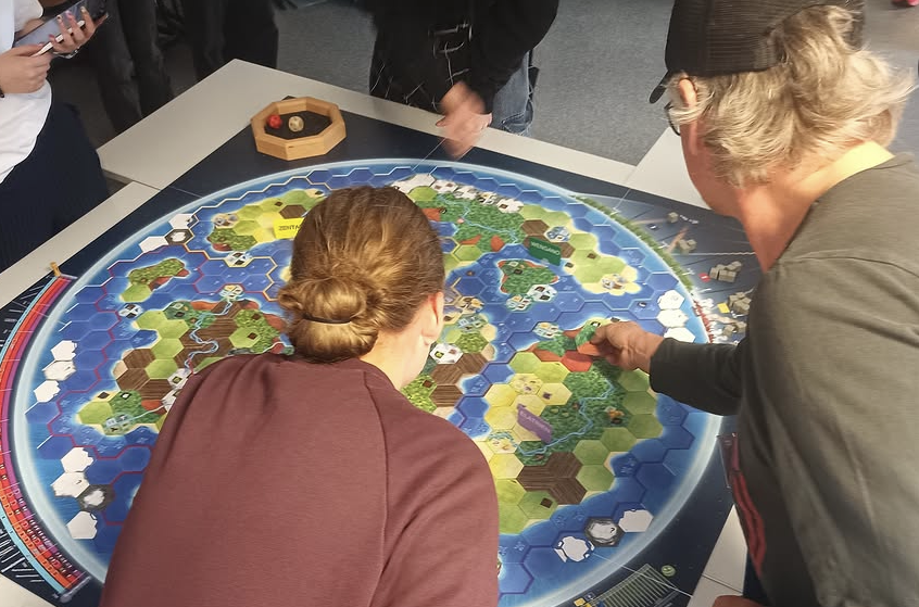 Zwei Personen von hinten aufgenommen beugen sich über das Weltklimaspiel Zwei Personen von hinten aufgenommen beugen sich über das Weltklimaspiel
