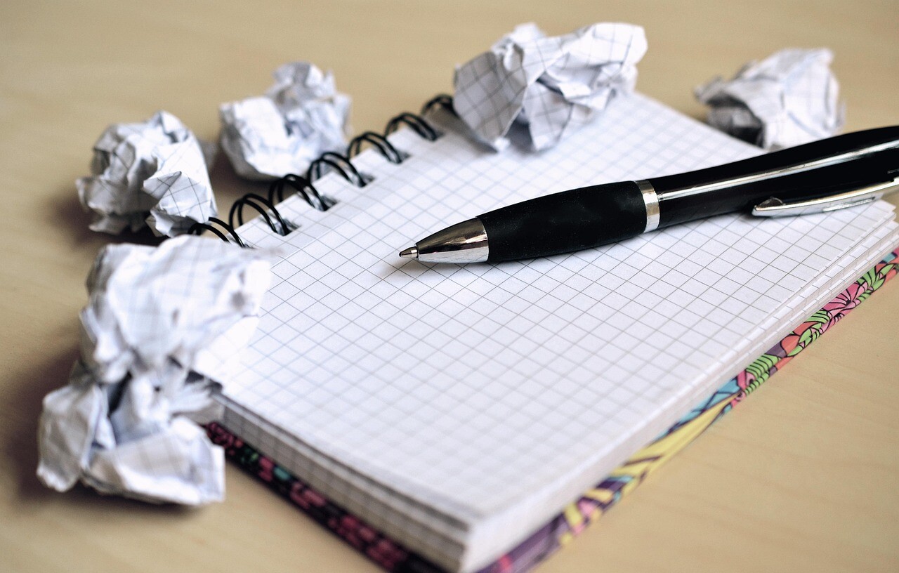 Ein Schreibblock mit zerknülltem Papier sowie ein Stift suggeriert den Schulbesuch..