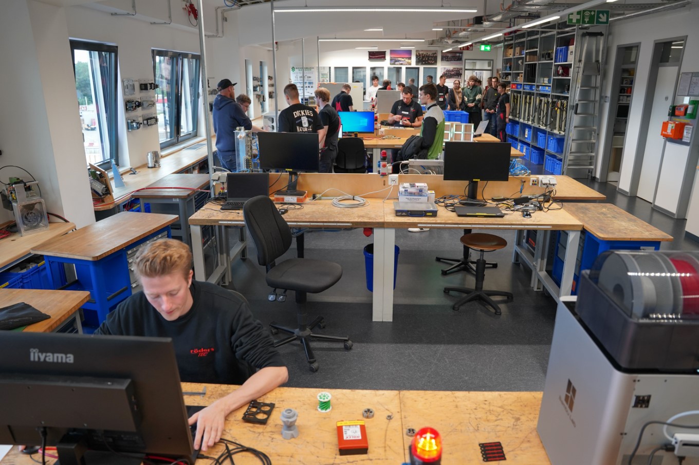 Mitarbeiter von Röders Tec infomiert andere Personen an verschiedenen Geräten über die Aufgaben im Betrieb.