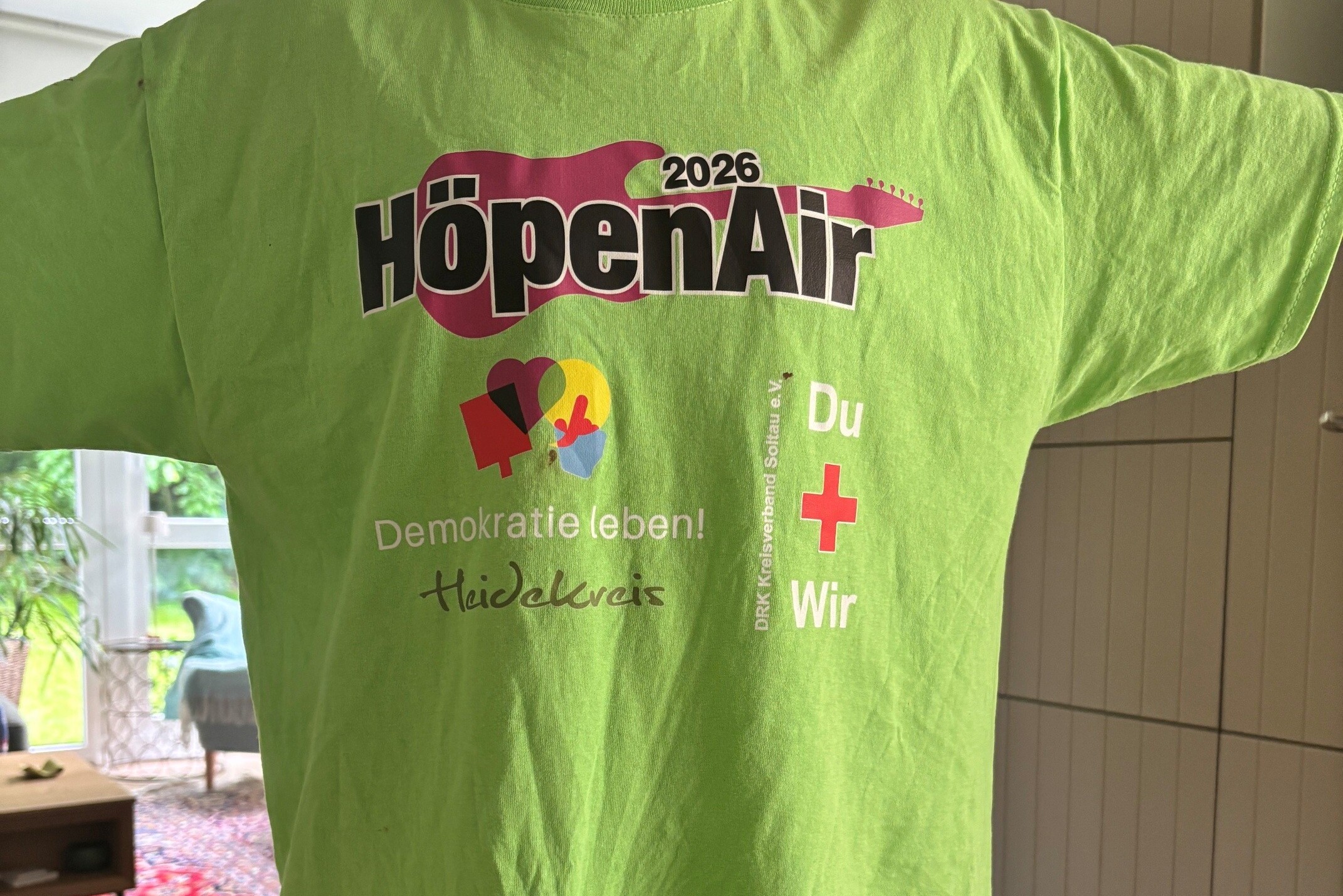 Ein grünes T-Shirt mit Werbung vom HöpenAir und Demokratie Leben Ein grünes T-Shirt mit Werbung vom HöpenAir und Demokratie Leben