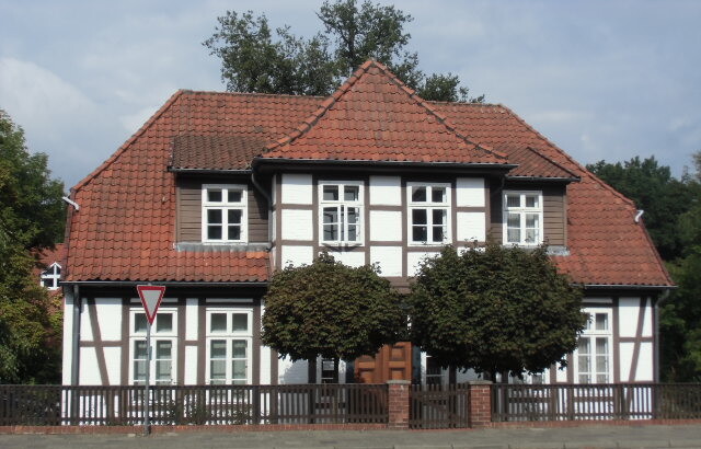 Ein Fachwerkhaus mit zwei Bäumen vor dem Eingang.