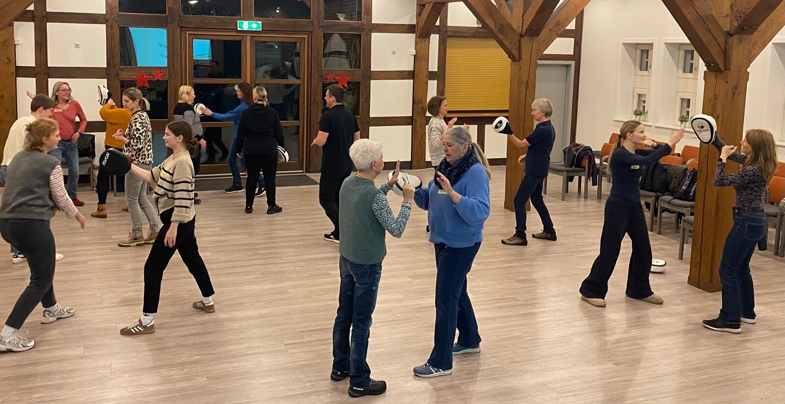 Viele Frauen sind in einem Raum und führen Übungen zur Selbstverteidigung durch.