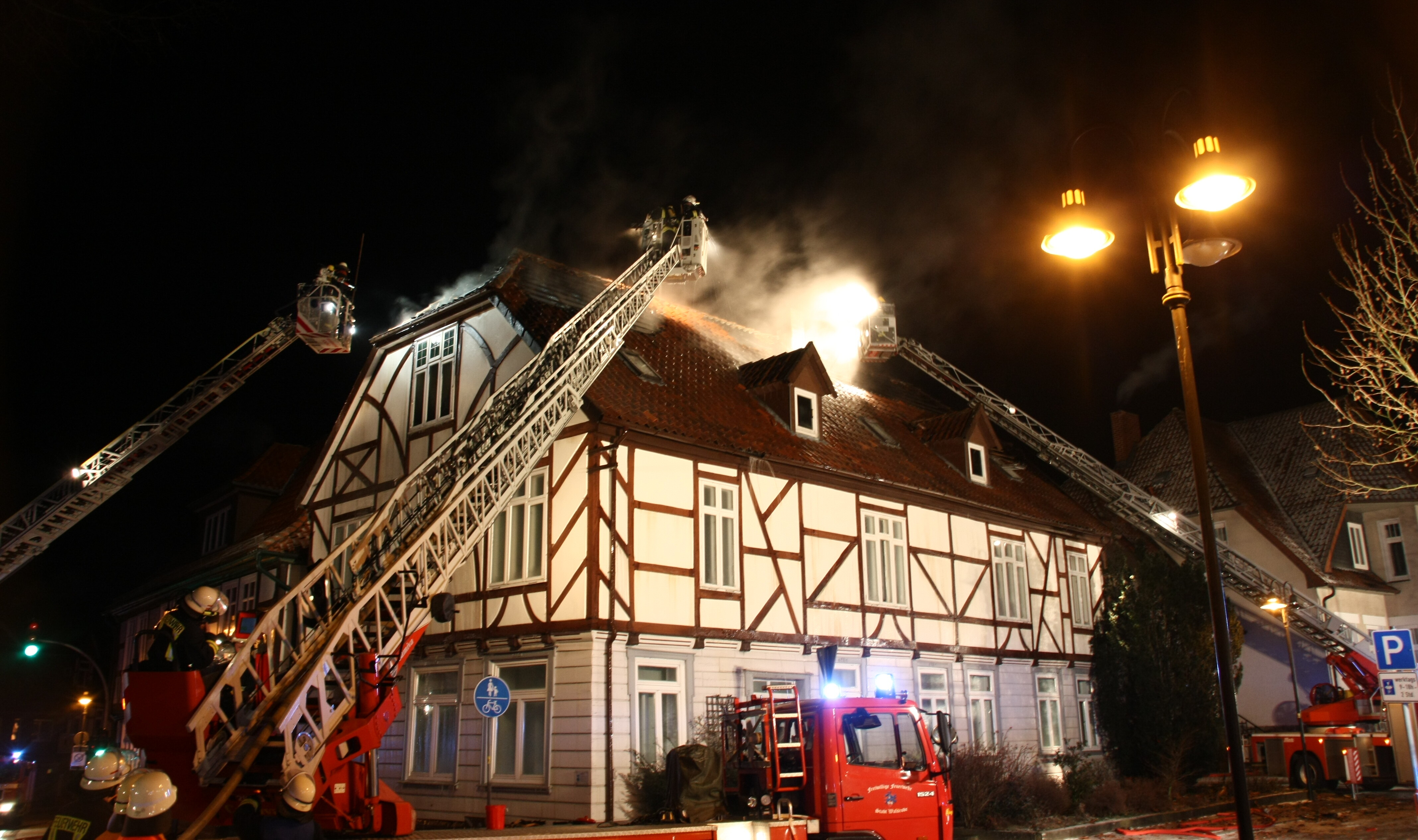 Mehrere Feuerwehrleitern befinden sich an einem Haus, um den dortigen Brand zu löschen.