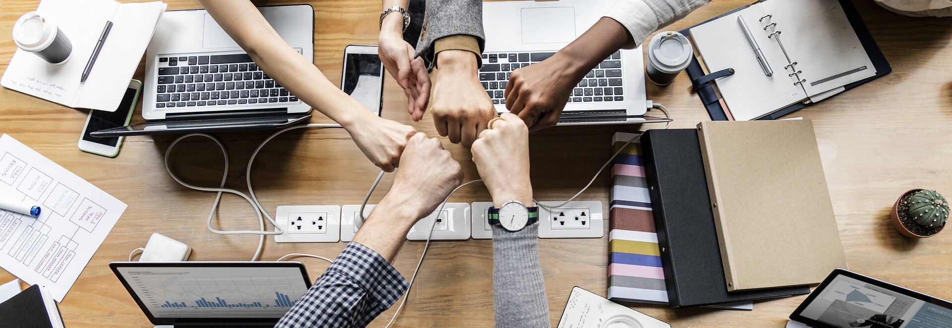 Hände als Fäuste kommen in der Mitte eines Tisches zusammen. Hände als Fäuste kommen in der Mitte eines Tisches zusammen.