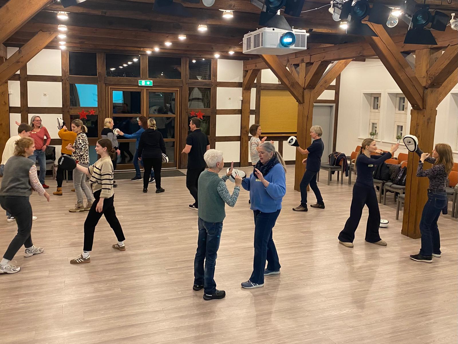 Viele Frauen sind in einem Raum und führen Übungen zur Selbstverteidigung durch.