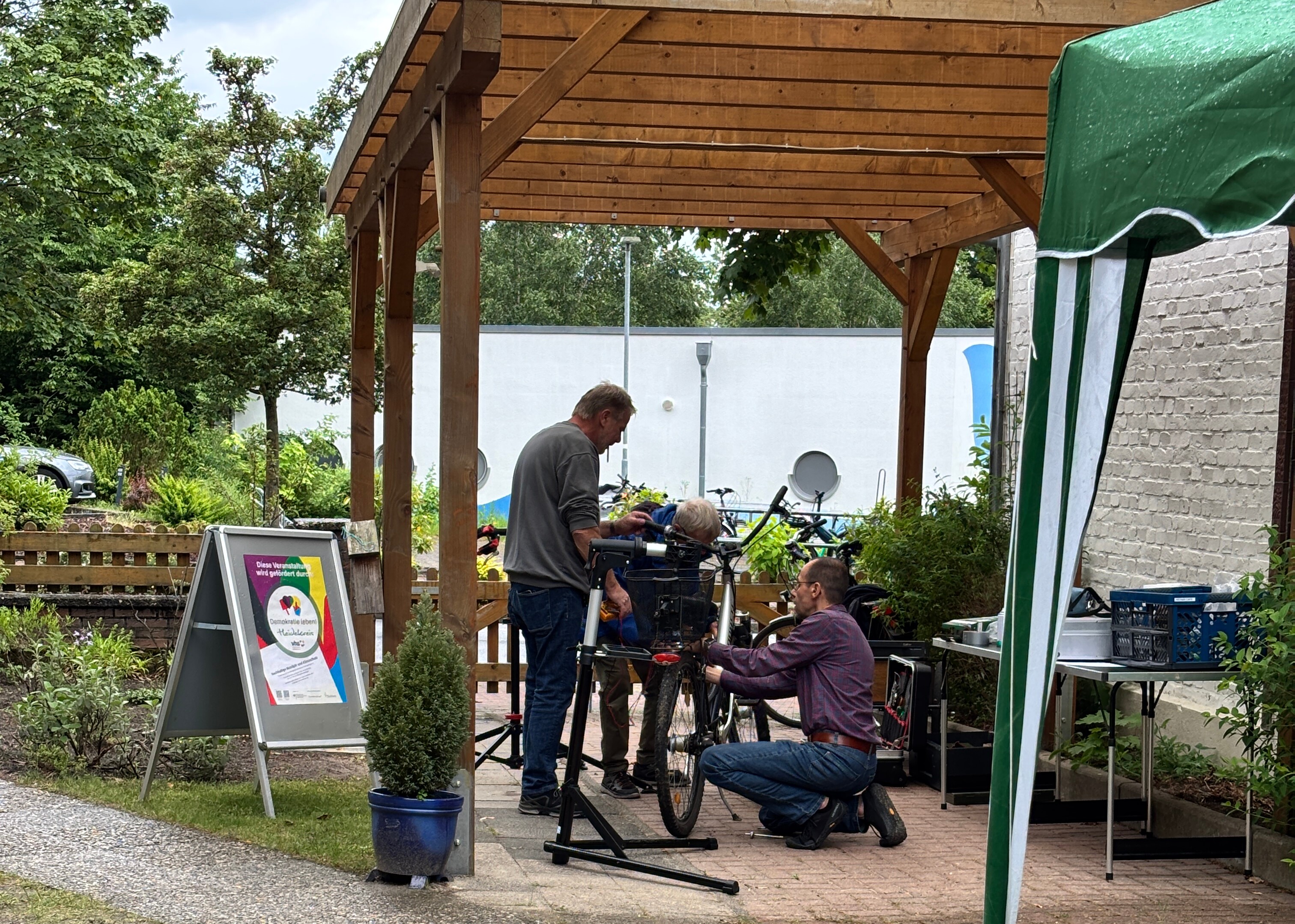 Zwei Männer reparieren ein Fahrrad unter einem Carport Zwei Männer reparieren ein Fahrrad unter einem Carport