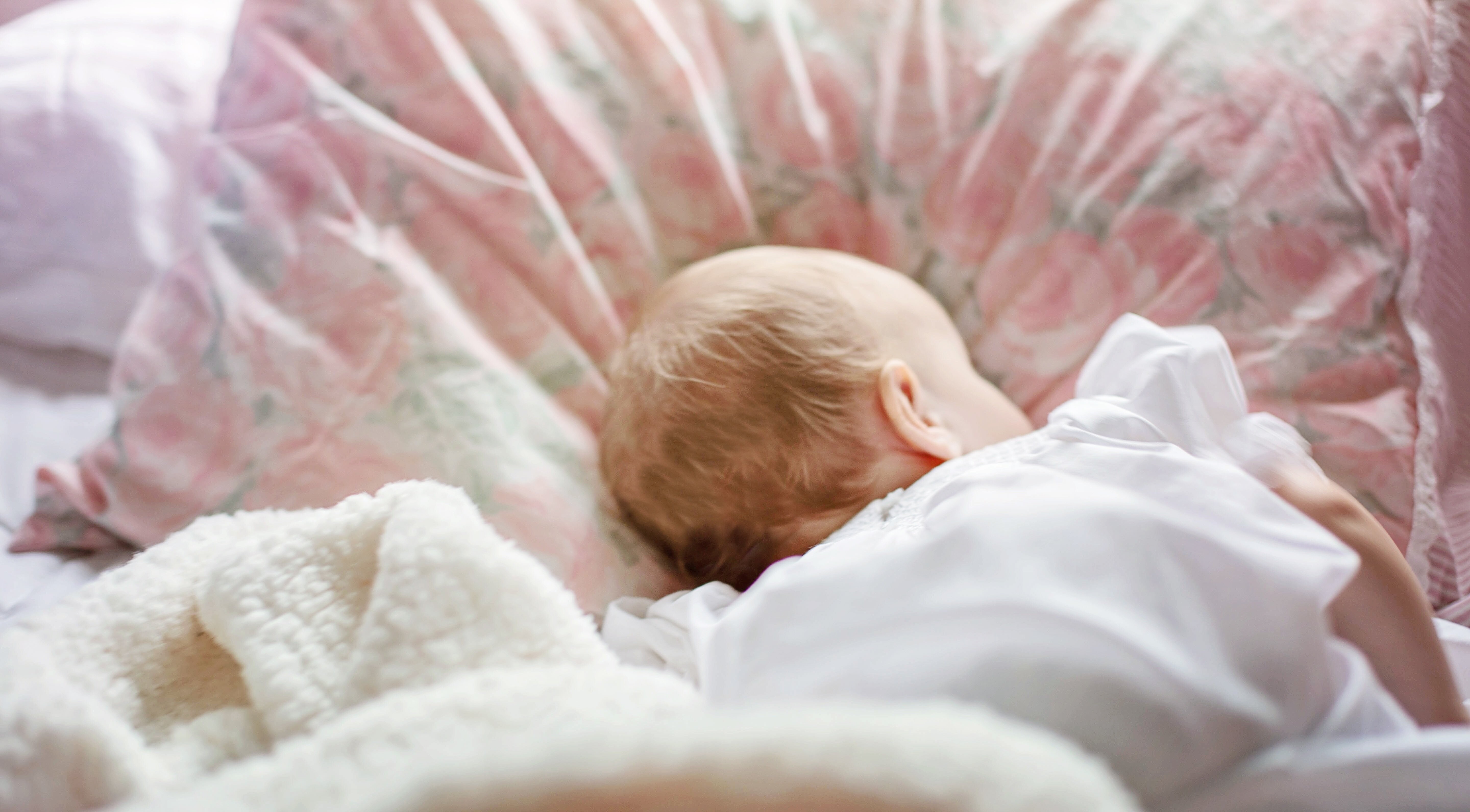 Ein Baby liegt auf einem Fell und schläft.